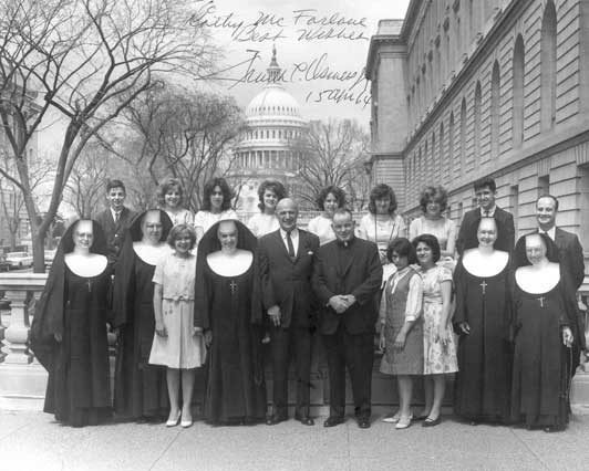 1961 graduates and staff of St. Joseph's Village pose with Congressman beside the Old House Office Building with the U.S. Capital in the distance.